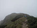 Das Gipfelkreuz taucht im Nebel auf