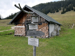 Vor der kleinen Hütte führt der Weg nach Nordwesten auf eine Almwiese