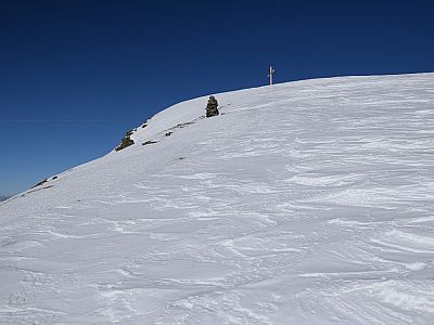 Nachdem die Hänge flacher werden taucht das vorgelagerte Gipfelkreuz auf
