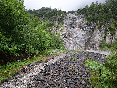 Erst durch den Wald, dann über ein Schotterfeld geht es auf eine Wand zu