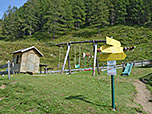 Wegweiser und Kinderspielplatz oberhalb der Alm