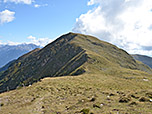 Wir wandern in einen breiten Wiesensattel hinunter