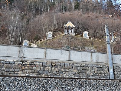 Abgetrennt durch Straße und Bahngeleise befindet sich ein Kreuzweg am Hang