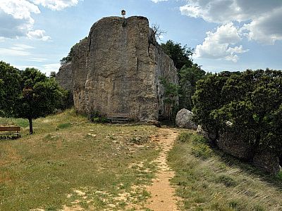 Hinter der Kapelle führt der Weg rechts an dem Felsen vorbei
