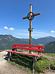 Am Gipfel thronen ein Holzkreuz und eine Rastbank